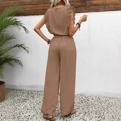 Woman wearing a brown jumpsuit standing against a white wall with a wooden panel above.