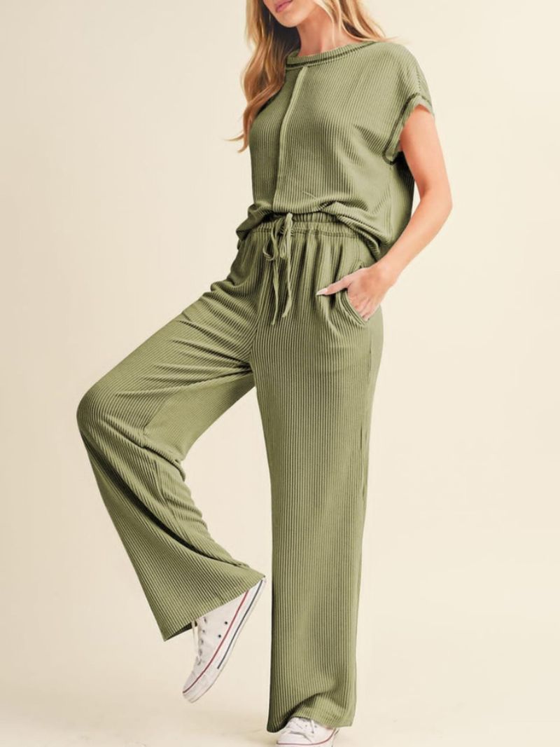 Woman wearing a green ribbed lounge set on a beige background