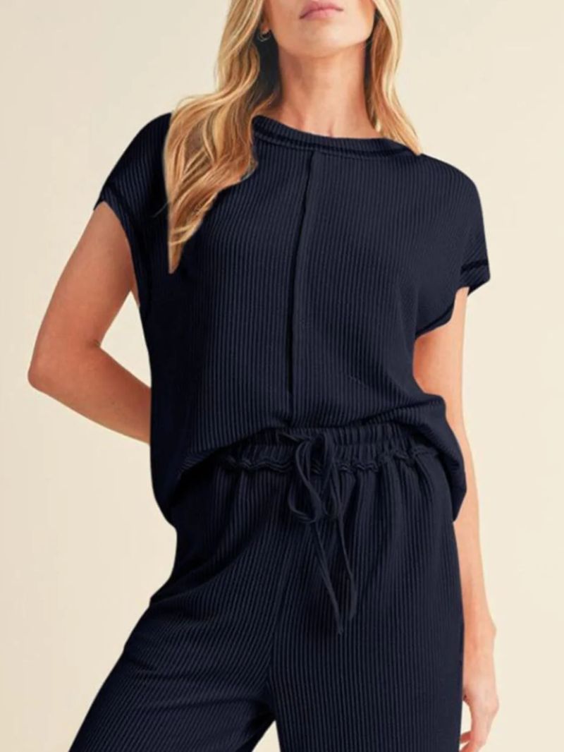 Woman wearing a navy ribbed top and pants on a beige background