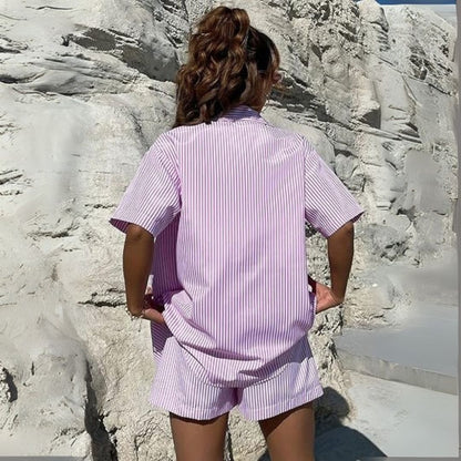 Person wearing a pink striped outfit standing against a rocky wall.