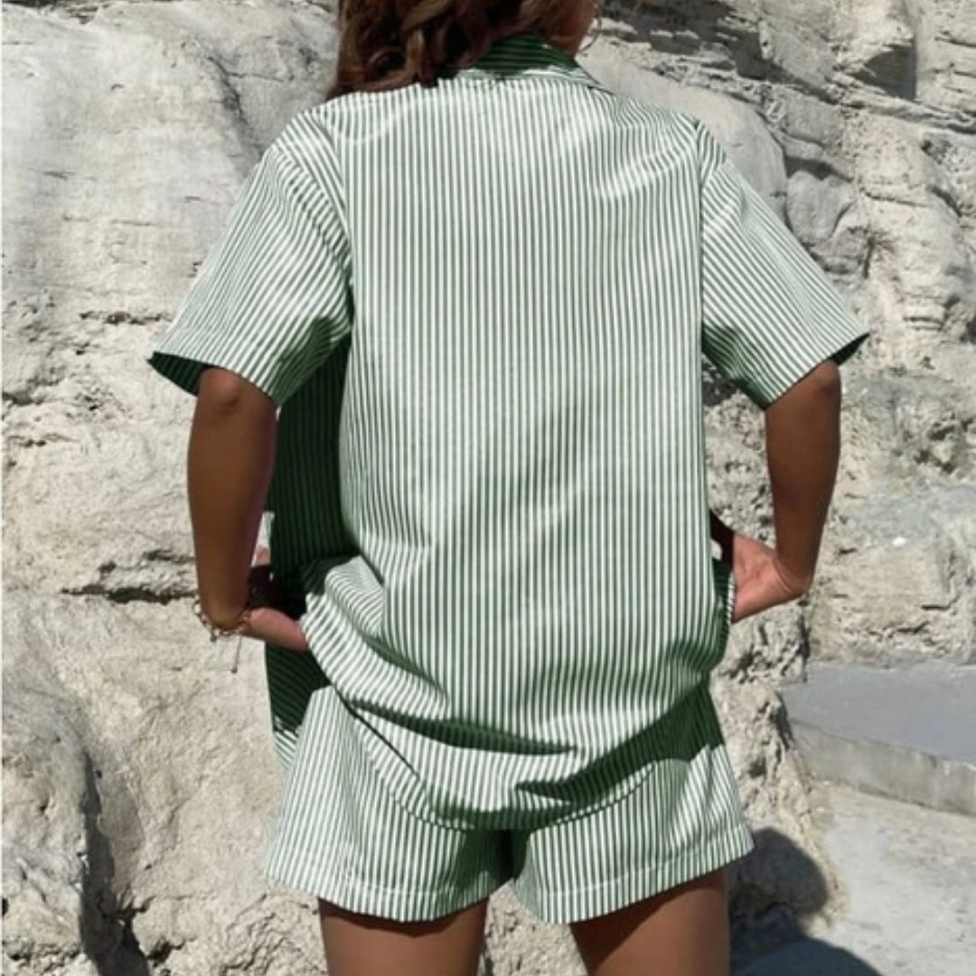 Person wearing a green and white striped shirt and shorts set against a rocky background.